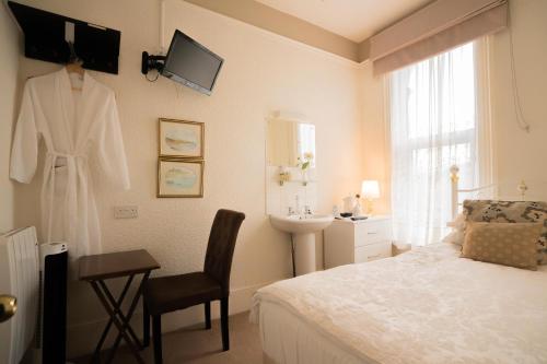 a bedroom with a bed and a robe hanging on a wall at Maison Dieu Guest House in Dover