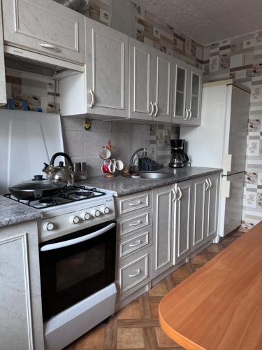 a kitchen with white cabinets and a stove top oven at Cozy Self Check-in CITY CENTRE apartment in Mažeikiai