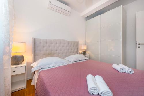 a bedroom with a pink bed with towels on it at Apartment APARTMAN MIA in Brodarica