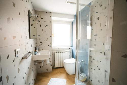 La salle de bains est pourvue de toilettes, d'un lavabo et d'une douche. dans l'établissement Le Finestre Apartments Muggia, à Muggia