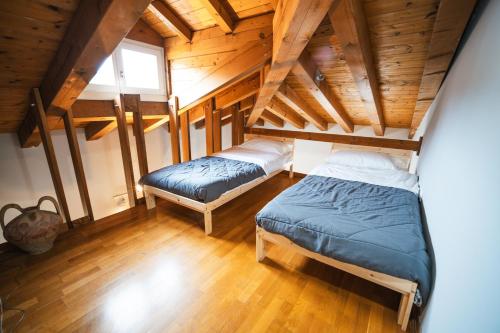 two beds in a room with wooden ceilings at Le Finestre Apartments Muggia in Muggia