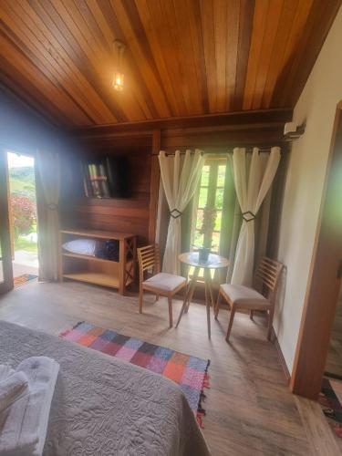 a bedroom with a bed and a table and chairs at Chalé Faisão Recanto Buscapé SFX in São Francisco Xavier