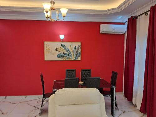 a dining room with red walls and chairs at APPARTEMENT NEW STANDING CITE CHIRAC YASSA in Yapoma