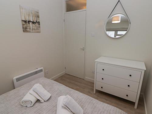 una camera bianca con letto e specchio di 21 Coedrath Park a Saundersfoot
