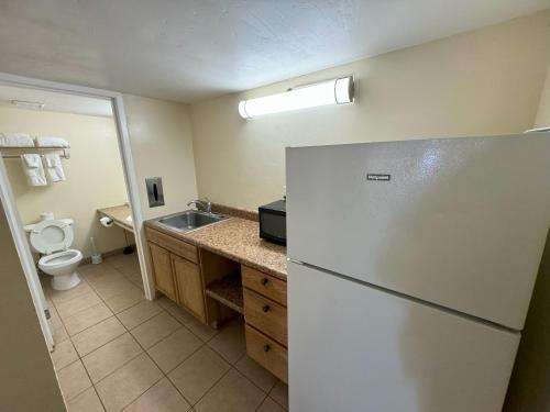 a kitchen with a refrigerator and a sink at Big Chile Inn & Suites in Las Cruces
