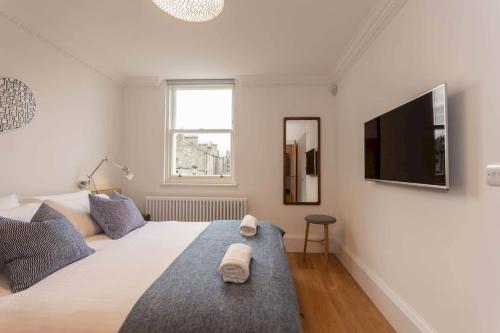 a white bedroom with a large bed and a flat screen tv at Luxury Penthouse on The Scores - Best View in St Andrews in St. Andrews