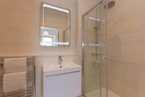 uma casa de banho com um chuveiro, um lavatório e um espelho. em Luxury Penthouse on The Scores - Best View in St Andrews em St. Andrews