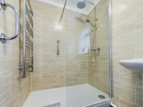 um chuveiro com uma porta de vidro ao lado de um lavatório em Exquisite Bungalow em Hessle