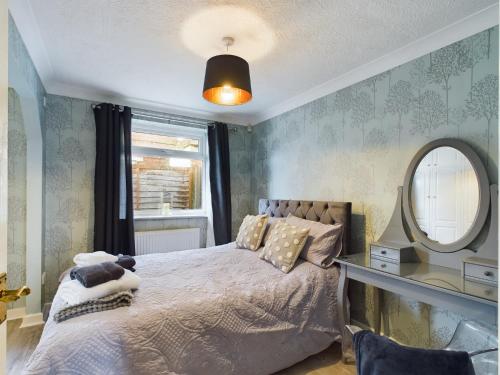 a bedroom with a bed with a mirror and a window at Exquisite Bungalow in Hessle