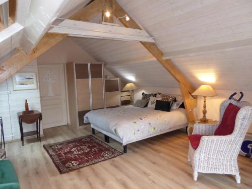 een slaapkamer met een bed en een stoel op zolder bij Location Ker Bihan in Saint-Lunaire