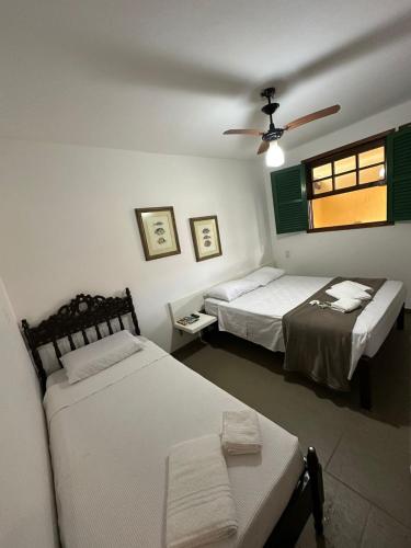 a bedroom with two beds and a table and a window at Pousada Via Mar Búzios in Búzios