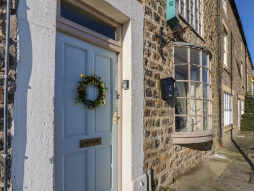 a blue door on a brick building with a wreath at 8 Market Place in Ripon