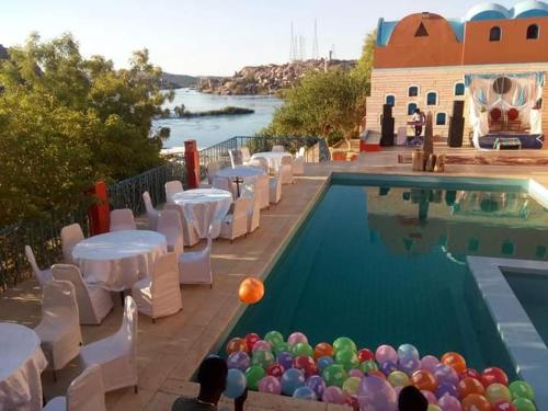 una piscina con mesas, sillas y globos en el agua en Resort Nubian Cataract, en Asuán