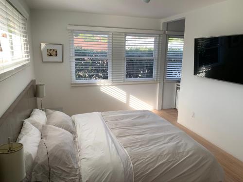 a white bedroom with a bed and a flat screen tv at Canyon View Cutie in San Diego
