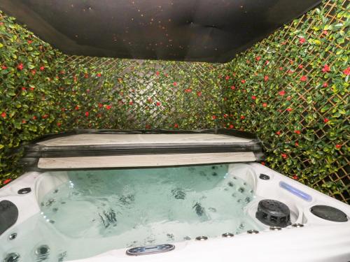 a bath tub in front of a wall of flowers at Crag View Cottage in Barrow in Furness