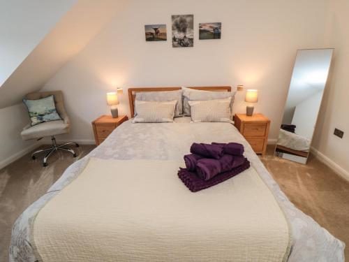 a large bed in a room with two lamps and a chair at Martindale Cottage in Whitby