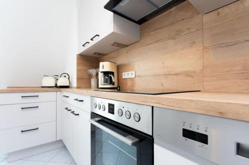 a kitchen with white appliances and a wooden counter top at BOHO CHIC Markkleeberg, in Seenähe, Familien Apartment, 8 min ins Leipziger Zentrum mit S-Bahn, Großer TV mit X Box in Markkleeberg