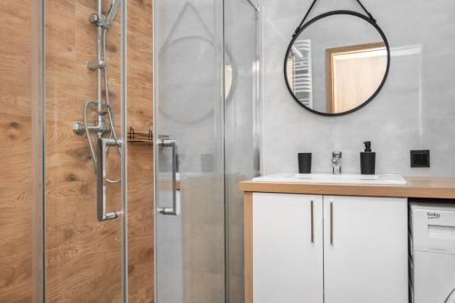 een badkamer met een douche met wastafel en spiegel bij Cosmo Apartments in Gdańsk