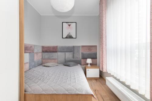 a bedroom with a bed in a room with a window at Cosmo Apartments in Gdańsk