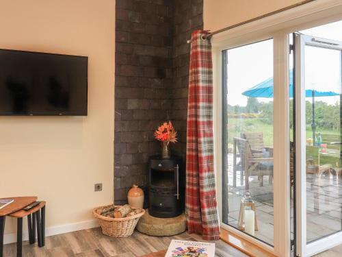 a living room with a fireplace and a sliding glass door at Pine Marten in Dornoch