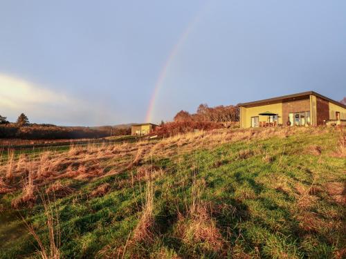 a house on a hill with a rainbow in the background at Pine Marten in Dornoch