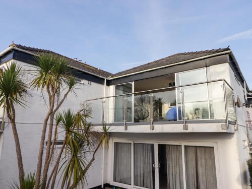 a white house with a balcony with palm trees at 36 Coedrath Park in Saundersfoot