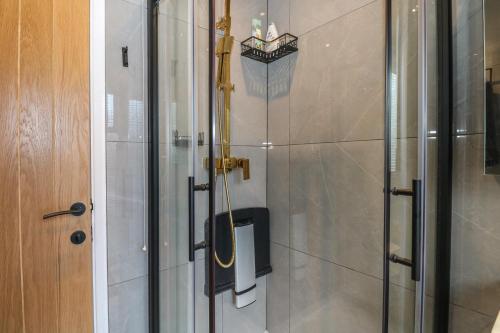 a shower with a glass door next to a wooden door at Beach Retreat in Seaford