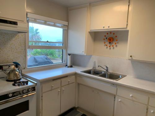 a kitchen with white cabinets and a sink and a window at Canyon View Cutie in San Diego