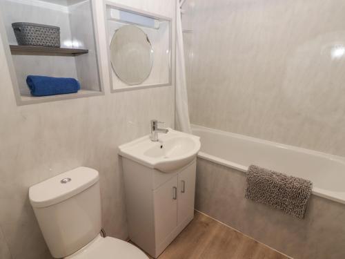 a bathroom with a toilet and a sink and a tub at 28 Coedrath Park in Saundersfoot