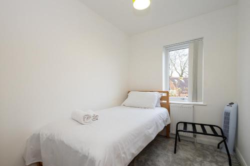 1 dormitorio con 1 cama, 1 silla y 1 ventana en Modern 4 Bed Home with Free Parking & Garden, en Mánchester