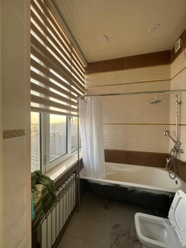 een badkamer met een bad en een raam bij The Rudaki Home stay in Doesjanbe