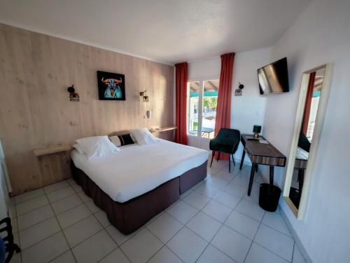サントマリー・ド・ラメールにあるL'auberge Camarguaiseのベッドルーム1室(ベッド1台、テーブル、デスク付)