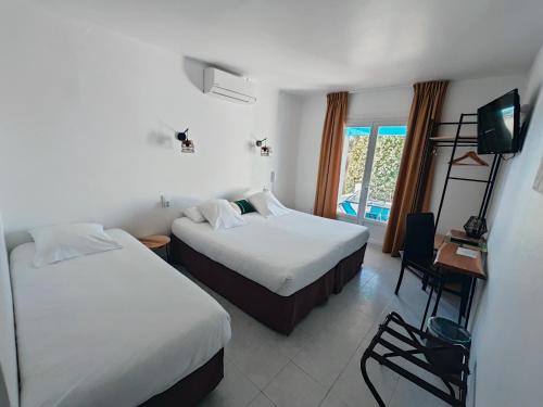 a hotel room with two beds and a television at L'auberge Camarguaise in Saintes-Maries-de-la-Mer