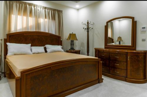 a bedroom with a large wooden bed and a mirror at Villa in Al Madinah in compound فيلا في المدينة in Al Madinah