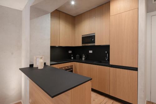 Una cocina con gabinetes de madera y una encimera negra. en Trinità UrbanHaven - Cuore di Cagliari, en Cagliari