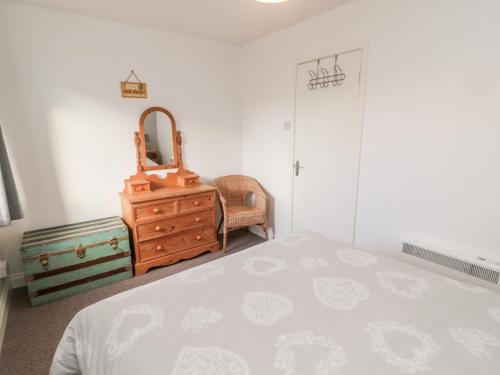 a bedroom with a bed and a dresser and a mirror at 22 Longstone Park in Chathill