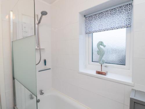 a bathroom with a shower and a window with a seahorse statue at 22 Longstone Park in Chathill