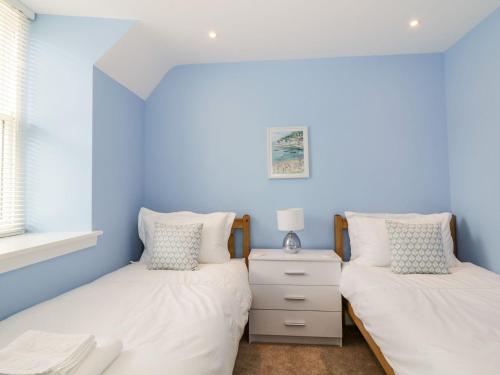 two twin beds in a bedroom with blue walls at Harts Cottage in Kirkcudbright