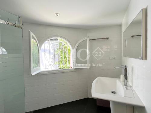 een witte badkamer met een wastafel en een raam bij Casa con gran jardín y jacuzzi en La Llosa 108D - INMO22 in Cambrils