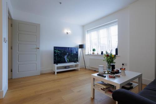 uma sala de estar com uma televisão e uma mesa em Lovely Modern 1-Bed Flat in Kingston em Kingston upon Thames