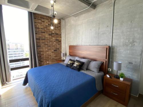 Un dormitorio con una cama azul y una pared de ladrillo en Lux 2 bedroom apartment, swimming pool, gym and free parking spot in Macro Plaza area, en Monterrey