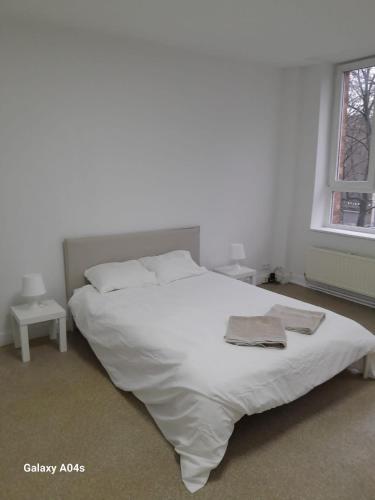 een wit bed in een witte slaapkamer met 2 tafels bij The Boulevard Apartment in Brussel