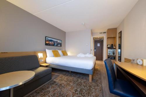 a hotel room with a bed and a couch at Novotel Maastricht in Maastricht