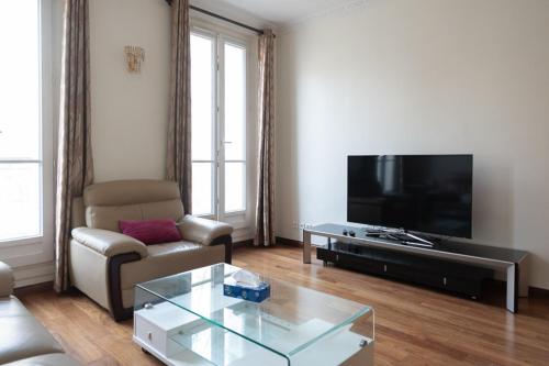 een woonkamer met een bank en een tv bij Spacious apartment with balcony in Parijs