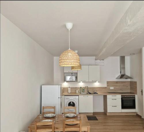 a kitchen with white cabinets and a pendant light at Spacieux Studio in Mer