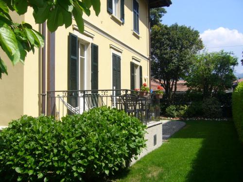 une maison avec un balcon et des buissons verts dans l'établissement Alpi Giulie, à Intra