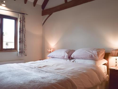 1 dormitorio con 1 cama con sábanas y almohadas blancas en The Old Dairy - Meadowbrook Farm, en Thame