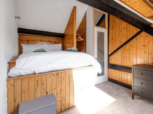 een slaapkamer met een bed met een houten muur bij Heather Cottage- Uk45889 in Farlam