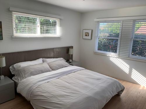 a white bedroom with a bed and two windows at Canyon View Cutie in San Diego