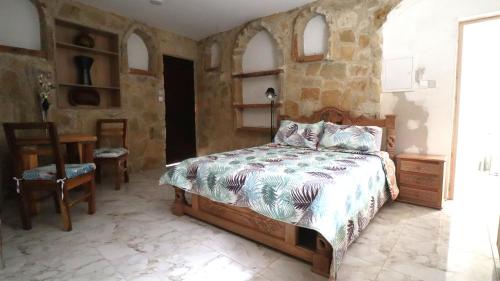 sypialnia z łóżkiem i kamienną ścianą w obiekcie La Hacienda Cyprus w mieście Limassol